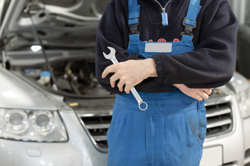 The mechanic with the arms of the cross with a automotive maintenance is background.