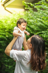 Mother is playing with her baby by holding up in the air. 