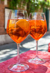 A glass with bright orange liquid, ice and a slice of orange, Spritz Aperol cocktail