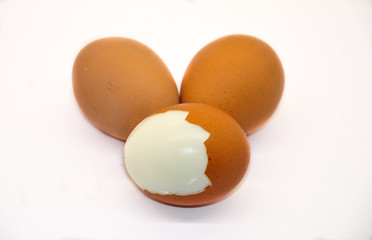 three eggs on white background. one peeled egg