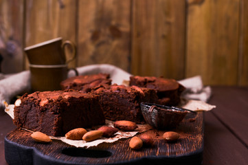 Brownie, Chocolate cakes with almonds on a wooden board, sprinkled with cocoa. Served homemade cakes. Top view. Free space for text.