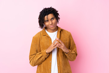 Young African American man with corduroy jacket over isolated pink background scheming something
