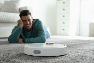 Man resting while robotic vacuum cleaner doing his work at home