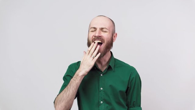 Portrait of a sleepy man yawning or feeling boredom isolated over white background. Concept of emotions