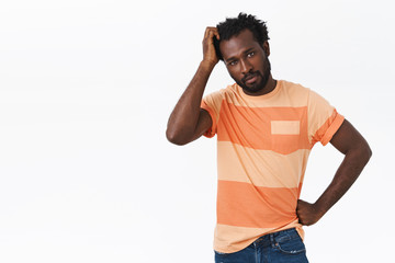 Fototapeta premium Troubled and unsure pretty african-american bearded guy have no idea how thing works, scratching head and looking questioned or confused, trying figure out how connect wires, white background