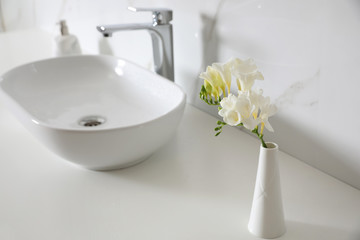Beautiful bouquet with white freesia flowers in bathroom, space for text