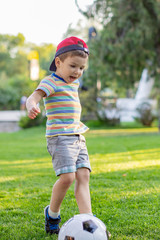 a little boy plays soccer in a city Park gives a pass kicks a ball