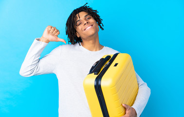 Young African American traveler man holding a suitcase proud and self-satisfied