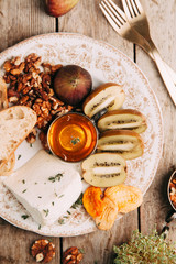 Flatley cheese plate with figs. Snacks for the company. Set of cheeses on a plate with honey and nuts.