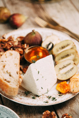 Flatley cheese plate with figs. Snacks for the company. Set of cheeses on a plate with honey and nuts.
