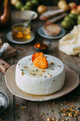 Fresh homemade cheese with dried apricot. Still life with hands, the chef prepares dishes. A circle of curd cheese on a plate.