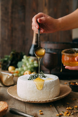  A large white round cheese on a plate. Curd cheese is watered with honey. The chef's hands prepare cheese.
