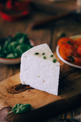  Composition with cheese and wine with cherry tomatoes. A large smooth round curd cheese on a plate.