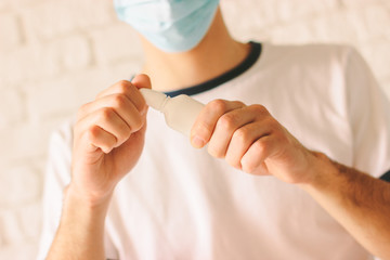 Closeup of young ill doctor with runny nose using nose drops. Confident sick man in medical...
