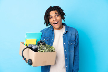 Young African American man making a move while picking up a box full of things with surprise and...