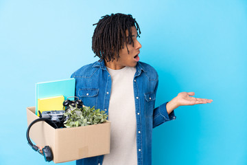 Young African American man making a move while picking up a box full of things with surprise facial...