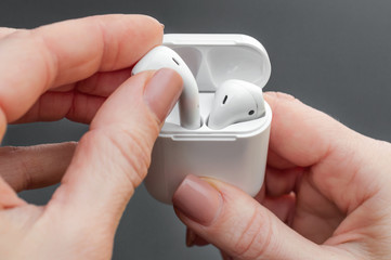 Hand holding case with wireless headphones. Close up.