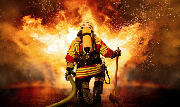 Feuerwehrmann kniet vor einem Feuer