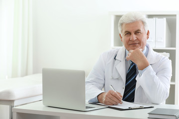 Fototapeta na wymiar Portrait of senior doctor in white coat at workplace