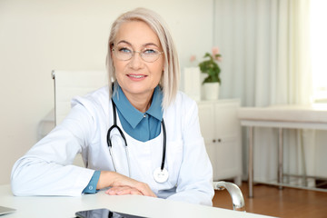 Portrait of mature female doctor in white coat at workplace