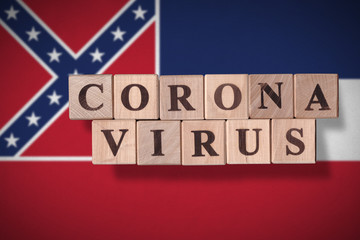 Flag of the state of Mississippi with wooden cubes spelling coronavirus on it. 2019 - 2020 Novel Coronavirus (2019-nCoV) concept, for an outbreak occurs in Mississippi, US.