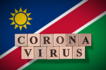 Flag of Namibia with wooden cubes spelling coronavirus on it. 2019 - 2020 Novel Coronavirus (2019-nCoV) concept, for an outbreak occurs in Namibia.