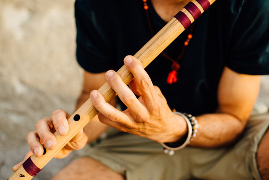 Man's hands playing indian flute bansuri, close up