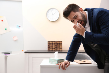 Obraz premium Sick young man at workplace. Influenza virus