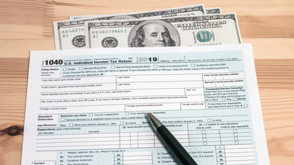 Fototapeta na wymiar US 1040 tax return form with 100 usd dollar bills and a pen
