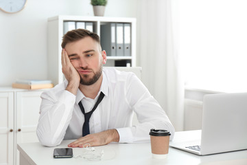 Lazy young man wasting time at table in office