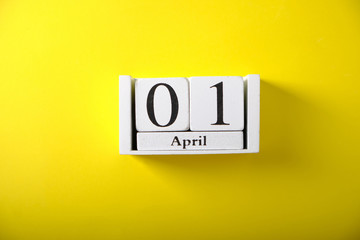 Wooden calendar with the date of April 1, on a yellow background
