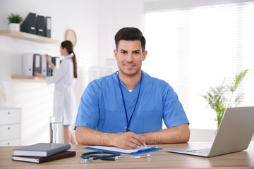 Fototapeta na wymiar Portrait of male doctor at table in modern clinic