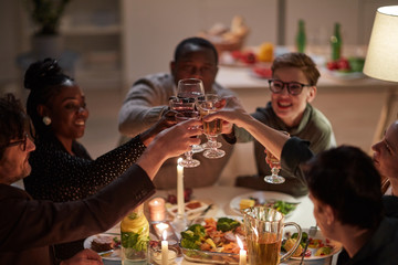 Group of young happy people celebrating with wine together at the table during holiday dinner