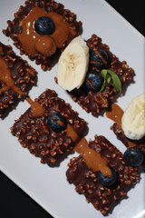 Chocolate dessert with nuts and fresh berries. Sweet snack for coffee biscuit in glaze and nut crumbs with fruit.