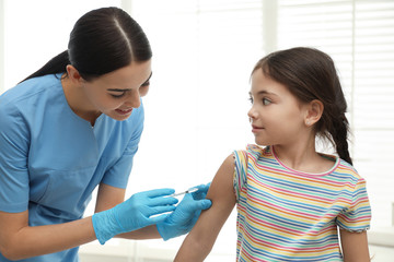 Doctor vaccinating little child in modern clinic