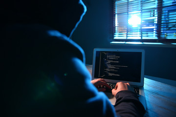 Hacker with laptop in dark room. Cyber crime