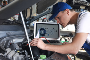 Mechanic with laptop doing car diagnostic at automobile repair shop