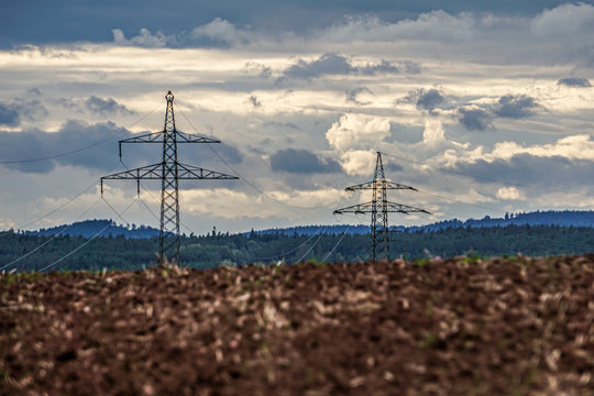 Strommasten &uuml;ber gepfl&uuml;gten Feld am Horizont