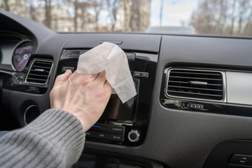 Man cleaning front dashboard of a car using antivirus antibacterial wet wipe (napkin) for protect...