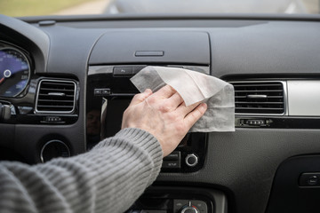 Man cleaning front dashboard of a car using antivirus antibacterial wet wipe (napkin) for protect...