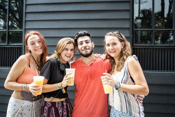 People from different ethnic groups with a juice in a plastic container in their hands and with bracelets with the lgtb flag