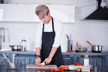Asian cook in the kitchen prepares food in a cook suit