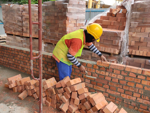 Brickwork by construction workers at the construction site. Workers laying the clay brick and stacked it together using mortar to form the wall. 