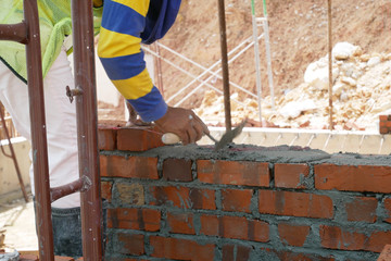 Brickwork by construction workers at the construction site. Workers laying the clay brick and stacked it together using mortar to form the wall. 