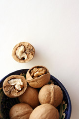 Walnuts in bowl on white background, top view with copyspace. 
