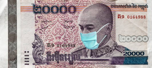 Coronavirus in Cambodia. Quarantine and global recession. 20000 Riel banknote with a face mask against infection. Global economy hit by corona virus covid19 outbreak and pandemic.  Coronavirus affects