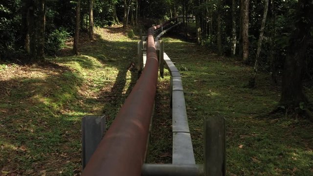 Flying over a rusted brown red oil pipe in the amazon rain forest
