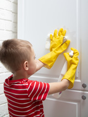 a child in yellow rubber gloves is cleaning. the child wipes the furniture from dust and dirt. Step...