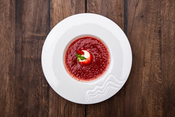 Strawberry Soup with Vanilla Ice Cream Ball. A plate of Cold creamy strawberry soup on a wooden table.
