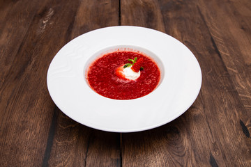 Strawberry Soup with Vanilla Ice Cream Ball. A plate of Cold creamy strawberry soup on a wooden table.
